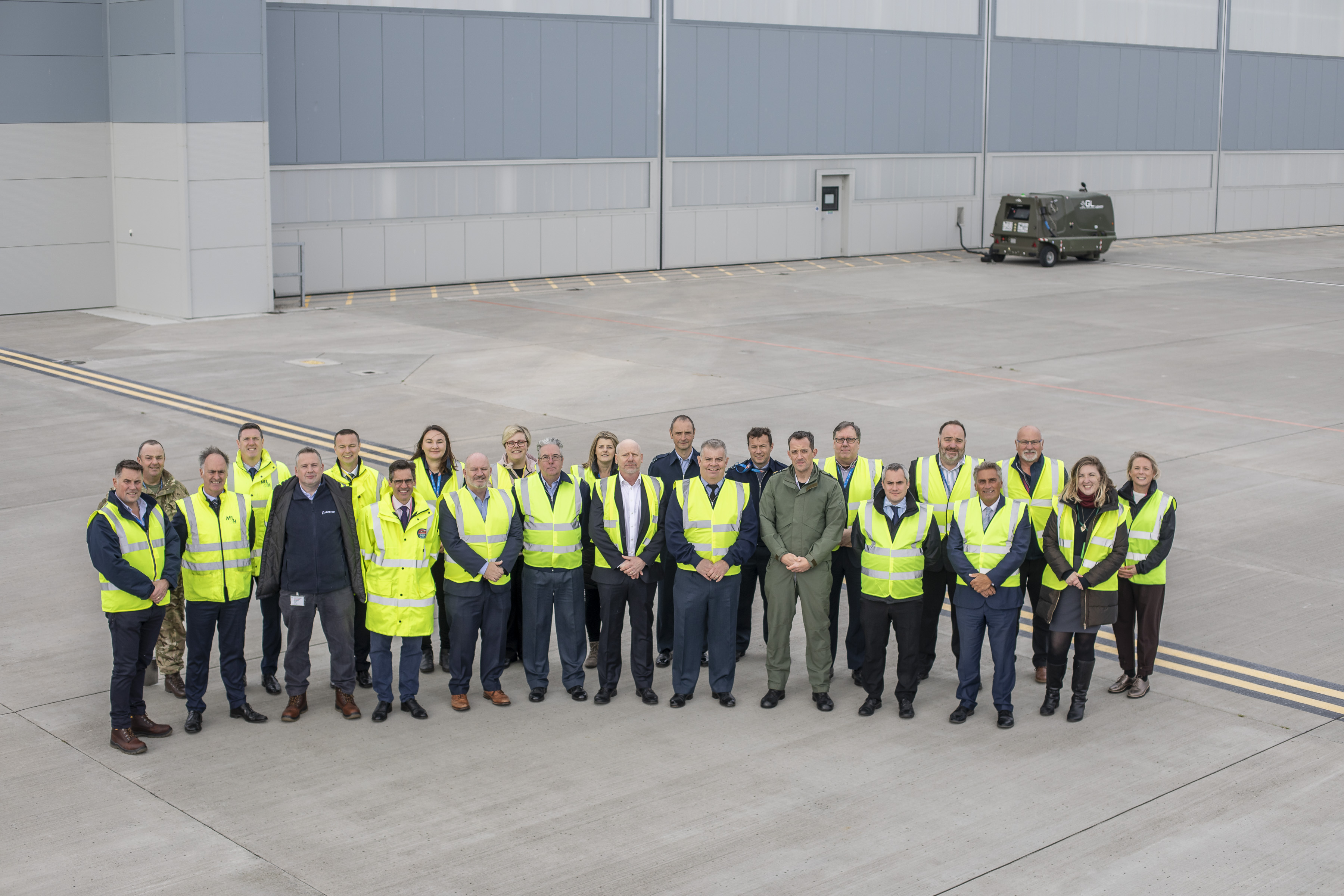 Image of personnel and civilians in high visibility jackets for group photo.